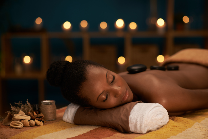 Young woman enjoying stone massage in luxury spa salon