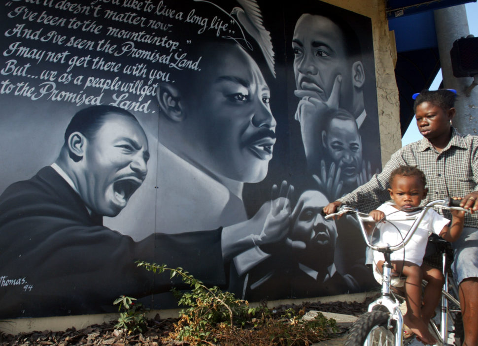 399903 06: Children ride a bicycle past a mural in honor of the slain civil rights leader Martin Luther King Jr. January 21, 2002 in Miami, Florida. (Photo by Joe Raedle/Getty Images)